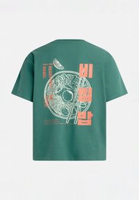 Grüne T-Shirt mit weißer Linienzeichnung einer Nudelschüssel, Essstäbchen, Limettenscheibe und orangefarbener Schrift in Englisch und Koreanisch auf der Rückseite.