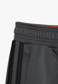 Grå tr�äningstights med en ribbade midja, som har svarta sidostrecks och en jämn textur. Inkluderar en synlig fick söm detalj.