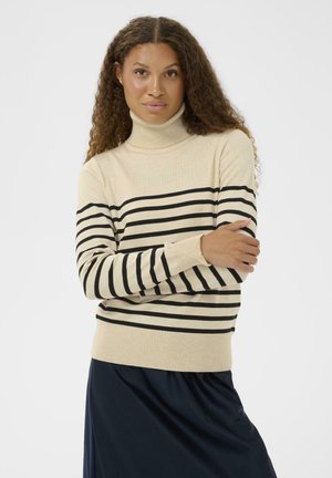 Beige gestreifter Rollkragenpullover mit schwarzen horizontalen Streifen. Gerippte Bündchen und Saum, mit einem taillierten Design. Darunter ein schlichte schwarze Rock.