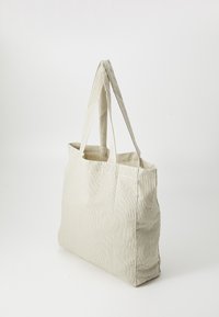 Borsa tote in tessuto beige a righe con due manici robusti, forma rettangolare e cuciture a sbalzo. Design semplice, leggera e spaziosa.
