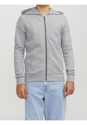 Szara bluza rozpinana na zamek z kapturem, wykonana z miękkiego materiału. Posiada długie rękawy i dwie przednie kieszenie. Połączona z jasnoniebieskimi dżinsami.