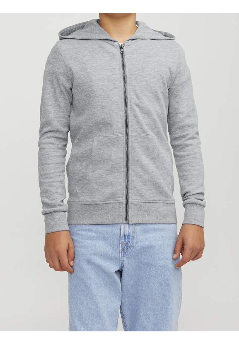 Sweat à capuche gris à fermeture éclair, fabriqué en tissu doux. Comprend des manches longues et deux poches avant. Associé à un jean bleu clair.