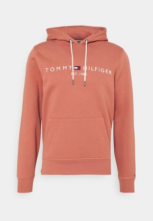 Roestkleurige hoodie met voorzak, witte trekkoorden en het logo "Tommy Hilfiger Est. 1985" in wit en marineblauw-rood op de borst.