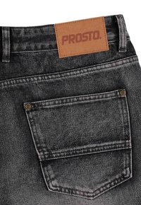 Szare dżinsy z denimu z skórzaną naszywką oznaczoną "PROSTO", posiadające tylną kieszeń oraz kontrastowe szwy.