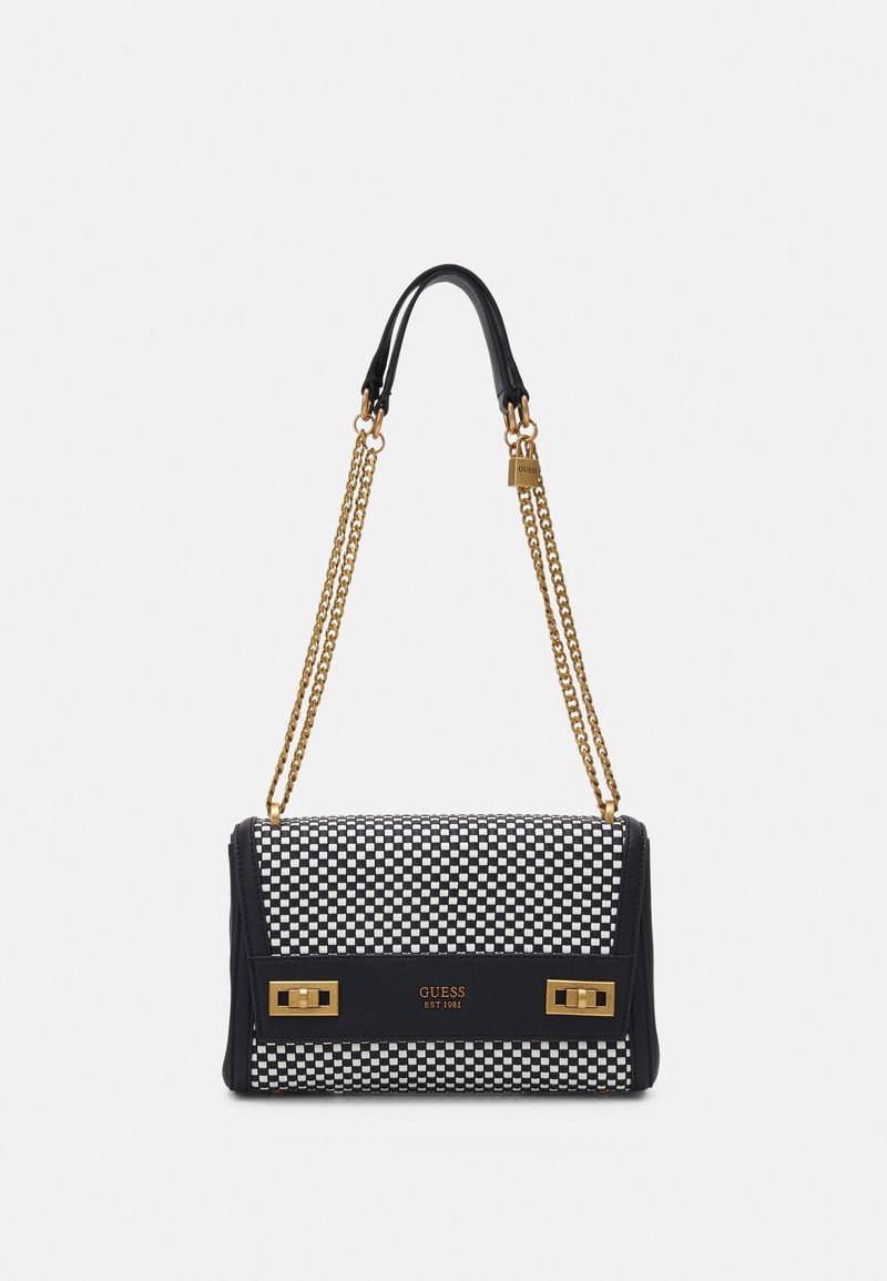 Borsa a spalla a scacchi bianca e nera con catene dorate e dettagli dorati, con il nome e il logo del marchio Guess sul davanti.