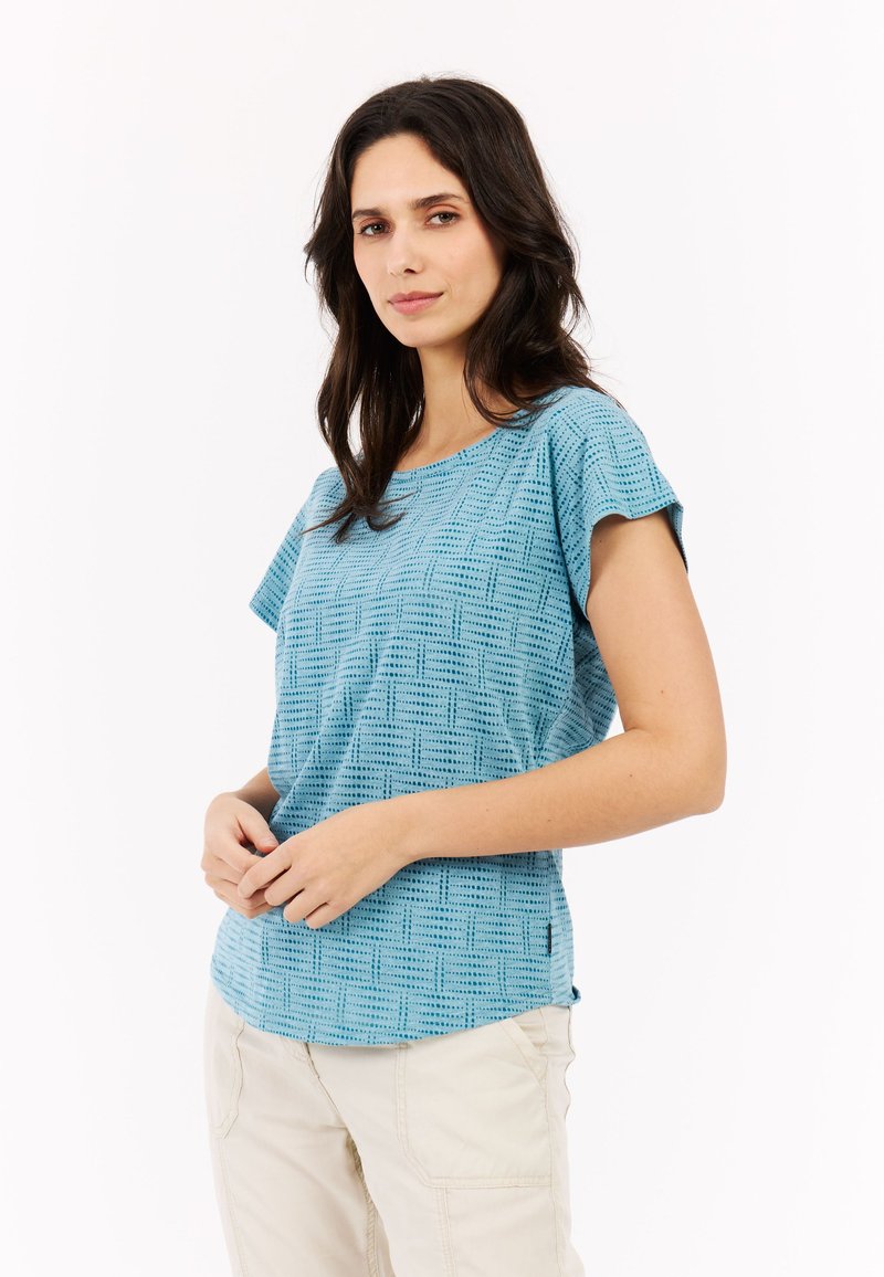 Šviesiai mėlyna trumpomis rankovėmis palaidinė su tekstūruotu tinklo raštu, apvaliu iškirpimu ir laisvu kirpimu, derinama su bežinėmis kelnėmis.