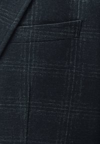 Dark plaid jacket fabric featuring a textured weave, subtle grey lines, and a single chest pocket without visible hardware accents.