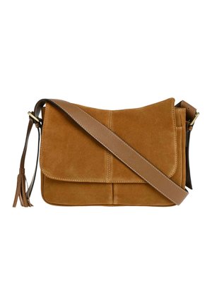 Sac bandoulière en suède marron avec une large sangle en cuir et un détail à pompon sur fond blanc.