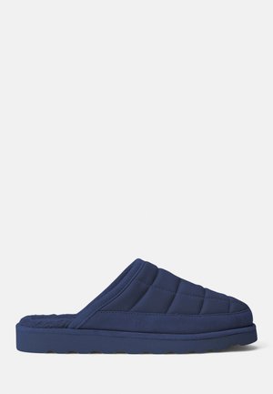 Navyblauwe gewatteerde slippers met een zachte, pluche binnenvoering en een dikke zool. De bovenkant heeft diagonale stiksels en een open achterkant ontwerp.