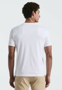 Witte katoenen t-shirt met korte mouwen, ronde hals en minimaal ontwerp; gladde textuur zonder zichtbare patronen of accenten.