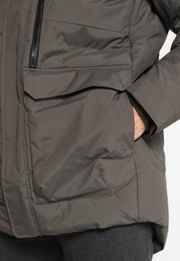 Giacca impermeabile grigia con tasca con zip e tasche a pattina quadrate, con una finitura testurizzata e polsini regolabili.