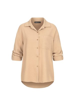 Beige gombos ing, texturált anyagból készült, gallérral, felgöngyölt ujjakkal és egy mellzsebből áll. Az alja enyhén ívelt.