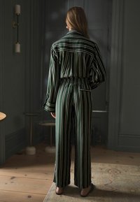 Stribet grøn pyjamas sæt med en afslappet pasform, der har en krave-top, elastisk talje og brede bukser. Glat stof og lange ærmer.