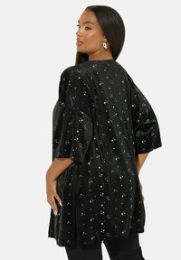 Mustat samettitoppi rentoa mallia, lyhyet hihat ja satunnaiset metalliset tähtikuviot. Sivupurgerot lisäävät liikkuvuutta.