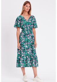 Abito midi floreale con una base verde scuro decorata da fiori rosa e bianchi, maniche corte a farfalla, scollatura a V e orlo a balze a strati.