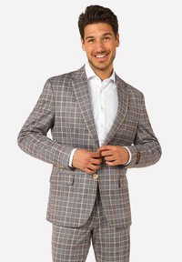 Blazer de cuadros grises con acentos en azul claro y amarillo, dos bolsillos frontales, solapas con muesca y cierre de botón dorado, combinado con una camisa blanca.