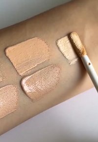 Échantillons de fond de teint de différentes teintes de peau sur un bras ; les textures sont crémeuses et lisses, avec des nuances allant du beige clair au bronzé foncé.