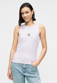 Μωβ αμάνικη μπλούζα με υφή ριπ και στρογγυλή λαιμόκοψη, με μικρό λογότυπο 'ck' σε μαρόν χρώμα. Συνδυάζεται με ανοιχτό μπλε τζην.