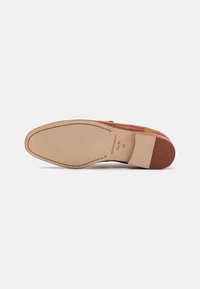 Scarpa in pelle marrone con una finitura liscia, caratterizzata da un punta arrotondata e una suola cucita a forma di mandorla. Logo del brand impresso sul tallone.