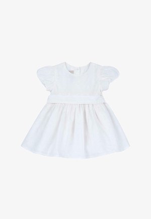 Robe blanche avec des manches bouffantes, taille empire et tissu texturé présentant des motifs floraux. Silhouette en A et décolleté rond.