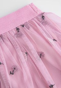 Różowa tkanina tiulowa z teksturowanym paskiem w talii, zdobiona haftowanymi kwiatowymi wzorami w odcieniach różu i zieleni. Widoczne półprzezroczyste warstwy.