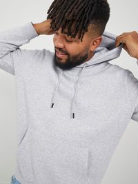 Szary bawełniany hoodie z przednią kieszenią, sznurkami i luźnym krojem. Tkanina ma gładką fakturę i melanżowy wzór.