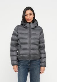 Γκρι μπουφάν puffer με εφαρμοστό κουκούλι, σχεδίαση με ραφές, μπροστινό φερμουάρ και δύο πλαϊνές τσέπες. Κατασκευασμένο από ελαφρύ, γυαλιστερό υλικό.
