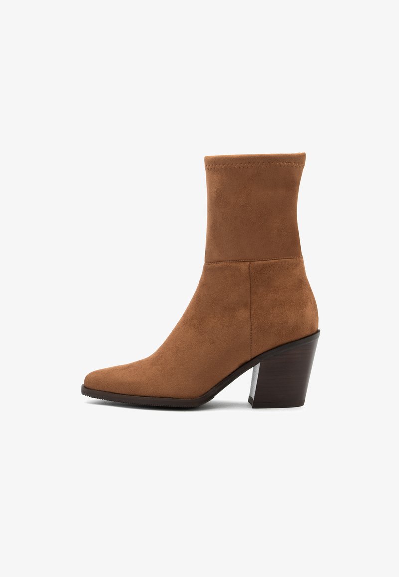 Stivale alla caviglia in suede marrone con punta affusolata e tacco di legno massiccio di media altezza, vista laterale su sfondo bianco.