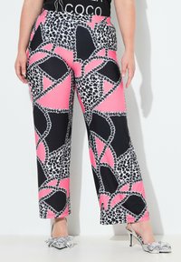 Pantaloni a gamba larga con stampa animale in nero, rosa e bianco. Presentano una vita non elasticizzata e una texture di tessuto liscia e leggera.