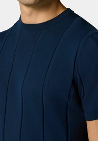 Maglietta a maniche corte di colore blu navy, lavorata a maglia, con righe verticali testurizzate e scollatura rotonda, caratterizzata da una finitura morbida e liscia.