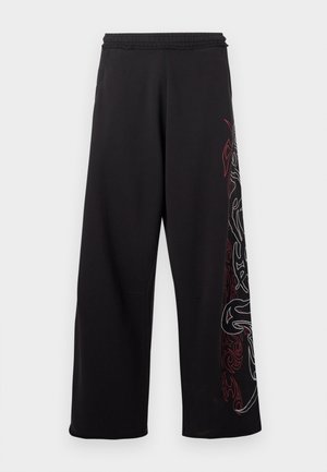 Pantaloni neri a gamba larga con vita elastica, caratterizzati da intricati disegni grafici rossi e argentati lungo un lato. Texture liscia.