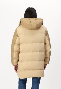 Kaki puffjakke med hette, med quiltet design og elastiske ermer. Stoffet ser glatt ut med en matt finish.