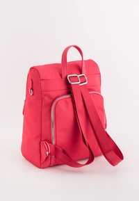 Rucsac roșu din nailon, cu bretele căptușite, mânere superioare și două buzunare externe cu fermoar. Textură netedă, formă rectangulară.