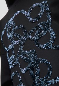 Tela negra con un intrincado diseño de lentejuelas azules que forman formas fluidas. La textura es suave con un efecto brillante de las lentejuelas.