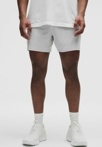 Ljusgrå idrottsshorts med en slät yta, med en enkel design. Kombineras med vita sneakers och vita strumpor.