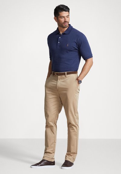 Marineblå kortermet polo med krage og tre-knapps placket, kombinert med khaki chinos og mørkebrune sneakers. Brun belte og klokke.
