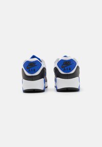 Čierne, šedé a biele tenisky Nike Air s modrými akcentmi. Majú polstrované golieriky a textúrované päty s detailom loga.