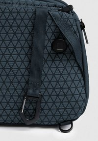 Borsa a tracolla blu con motivo a diamante, tessuto testurizzato, tracolla regolabile e moschettone nero per l'aggancio.