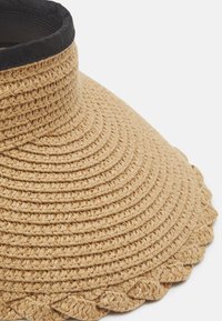 Sombrero de paja de ala ancha con una textura tejida en beige, que presenta una banda de tela negra alrededor del borde superior y un acento en forma de ondas en el borde de la ala.