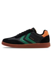 Fekete sneaker zöld chevron díszítéssel, velúr és szintetikus anyagból, narancssárga saroktabbal és barna gumitalppal. Fűzős dizájn logó részlettel.
