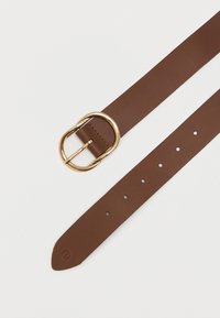 Hnedý kožený opasok s hladkým povrchom a okrúhlou zlatou sponou. Obsahuje niekoľko zárezov pre nastaviteľnú veľkosť.