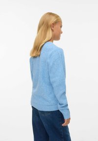 Ljusblå tröja i mjukt stickat material, med rund hals, långa ärmar och ribbade muddar och nederkant. Buren med mörkblå jeans.