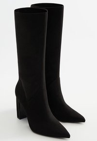 Bottes noires montantes en suède doux, avec un bout pointu et un talon bloc, proposant un design sans couture et sans matériel visible.