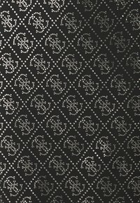 Svart material med ett diamantmönster prytt med silvernitar, som visar en dekorativ logotyp i ett upprepat upplägg.