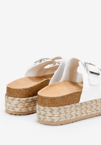 Sandali platform bianchi con fondo in sughero, suola in juta intrecciata e dettagli in metallo argentato. Texture liscia e forma arrotondata.