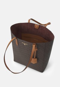 Borsa tote in tela monogram marrone con manici in pelle beige e interno coordinato. Presenta una chiusura a scatto, una tasca e dettagli in metallo marchiato.