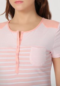 Top de manga corta en rayas rosa y blancas, con una tapa de botones, tejido ligero y un pequeño bolsillo en el pecho.