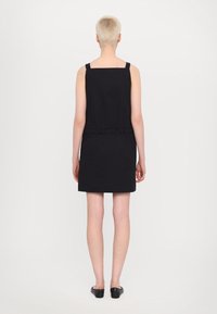 Vestido negro sin mangas con escote cuadrado, cintura ajustada y dobladillo a la altura de la rodilla. Elaborado en un tejido suave y elástico.