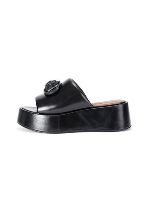 Sandale à glissière en cuir noir avec un bout ouvert, un dessus rembourré et un ornement décoratif rond. Dispose d'une semelle épaisse.