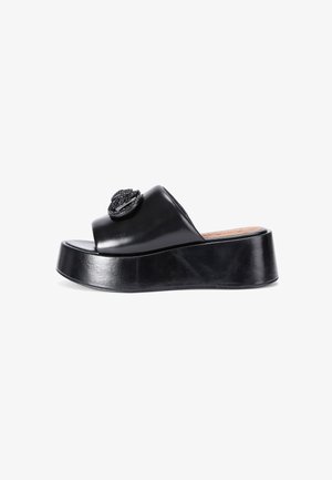 Black leather slide sandal with open toe, padded upper, and a round decorative embellishment. Features a thick platform sole.